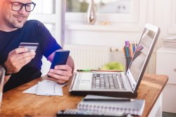 Homme avec carte de crédit sur un smartphone au bureau à la maison